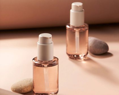 two beauty product bottles against a beige background