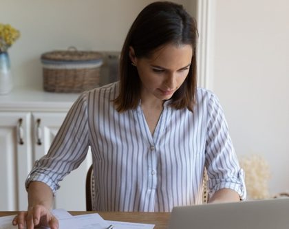 woman sitting at a desk focused on her laptop with scattered papers